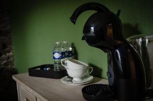 a tea kettle on a counter with a cup on a table at B&B Au Canard in La-Roche-en-Ardenne
