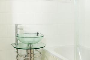 um lavatório de vidro numa mesa de vidro na casa de banho em Ping-Pong Paradise em Crawley