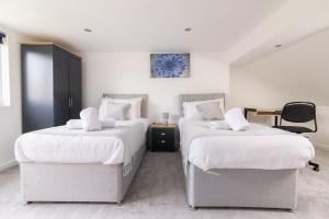 2 Betten in einem Zimmer mit einem Tisch und einem Stuhl in der Unterkunft Ping-Pong Paradise in Crawley
