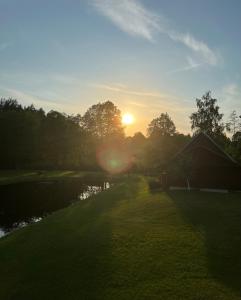 a sunset over a river with a house and trees at Stripeikių Bitė in Varniškės I +13 photos
