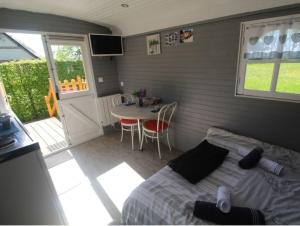 ein Schlafzimmer mit einem Bett und einem Tisch sowie eine Küche in der Unterkunft La roulotte du bois du fil in Vassonville