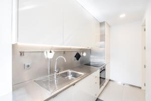 a kitchen with white cabinets and a sink at VIVA Nanda's Place in Porto