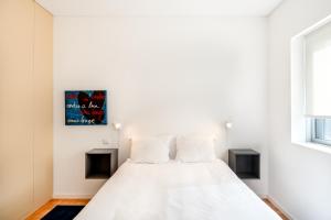 a bedroom with a white bed with two windows at VIVA Nanda's Place in Porto