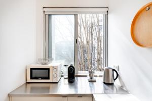 a kitchen counter with a microwave and a window at VIVA Nanda's Place in Porto