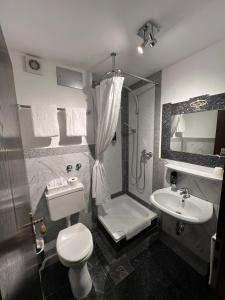 a bathroom with a toilet and a sink and a shower at Runa´s Hotel in Hallbergmoos