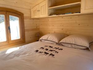 a bed in a log cabin with two pillows at Chez Sophie et Gilles in Monistrol-sur-Loire