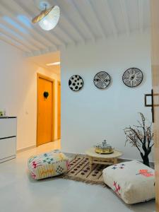 Le Majorelle Cozy Flat في مراكش: غرفة معيشة مع طاولة وساعتين على الحائط