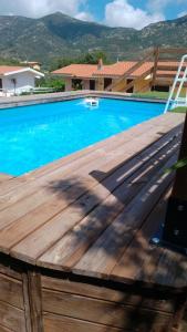 een blauw zwembad met een houten dek en een stoel bij Villa Susy Solanas -IUN R5389 in Solanas