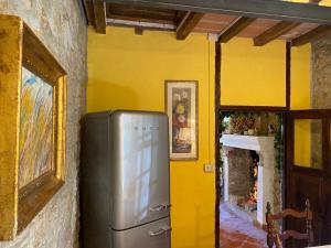 a kitchen with a refrigerator and a yellow wall at Villa Chicca in Neviano degli Arduini