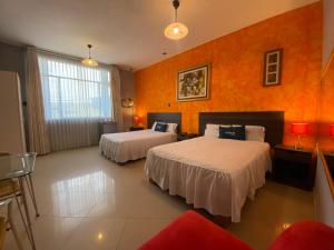 um quarto de hotel com duas camas e paredes cor de laranja em Suite Apart Miraflores em Piura