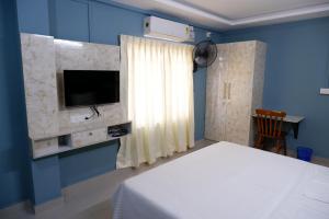 1 dormitorio con 1 cama y TV en una pared azul en Haya Residency, en Alleppey