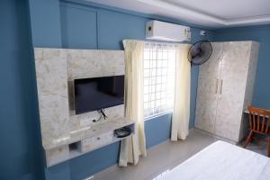 sala de estar con TV y pared azul en Haya Residency, en Alleppey