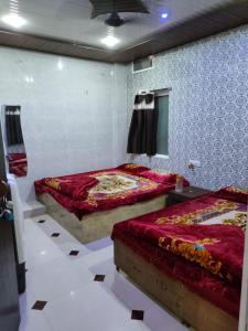 Duas camas num quarto com paredes brancas em Tamrakar Hotel and Restaurant em Ujaim