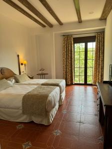 a bedroom with two beds and a large window at Hotel Rural Cazorla Posada del Cordobés in Cazorla