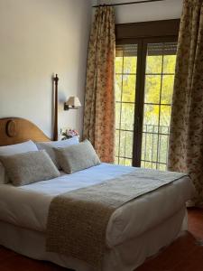 sypialnia z dużym łóżkiem i dużym oknem w obiekcie Hotel Rural Cazorla Posada del Cordobés w mieście Cazorla