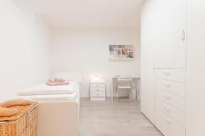 ein weißes Schlafzimmer mit einem Bett und einem Schreibtisch in der Unterkunft Contrada della Fontana Luxury Apartment in Levico Terme