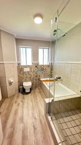 a bathroom with a tub and a toilet and a shower at Greenpoint Mews 17, Plettenberg Bay in Plettenberg Bay