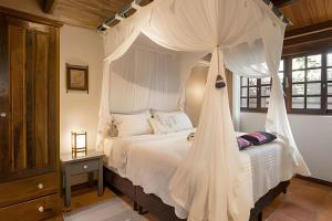 a bedroom with a white bed with a canopy at Casa Thai Linda na Praia in Barra de Ibiraquera