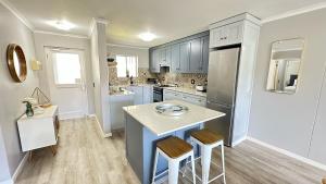 a kitchen with blue cabinets and a kitchen island with stools at Greenpoint Mews 17, Plettenberg Bay in Plettenberg Bay