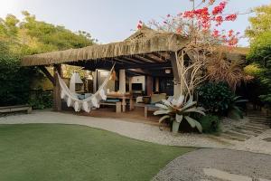 a pavilion with a table and a hammock in a garden at Casa Thai Linda na Praia in Barra de Ibiraquera