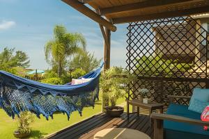 a blue hammock hanging on a porch with a garden at Villa Sayuri in Barra de Ibiraquera