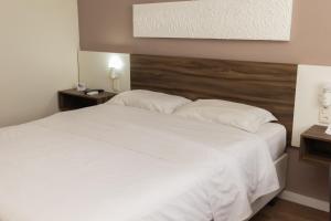 1 dormitorio con 1 cama grande con sábanas y almohadas blancas en Swan Rio Grande, en Río Grande