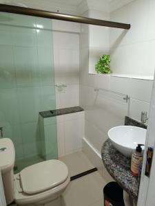 Baño blanco con aseo y lavamanos en Aconchego Vila Rica - Mariana, en Mariana