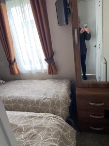 eine Person, die ein Bild von einem Spiegel in einem Schlafzimmer macht in der Unterkunft Luxury Lodge 1477 West Sands in Selsey