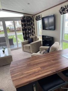 ein Wohnzimmer mit einem Tisch, einem Sofa und einem TV in der Unterkunft Luxury Lodge 1477 West Sands in Selsey