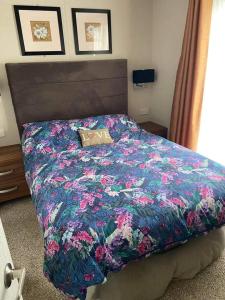 1 Schlafzimmer mit einem Bett mit Blumendecke in der Unterkunft Luxury Lodge 1477 West Sands in Selsey