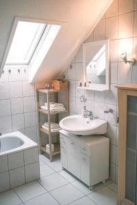 ein weißes Badezimmer mit einem Waschbecken und einem Dachfenster in der Unterkunft FERIENWOHNUNG "Deichort" Meppen in Meppen + 13 Fotos