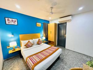 1 dormitorio con 1 cama grande y pared azul en Hotel Golden Saffron - Punjabi Bagh Delhi en Nueva Delhi