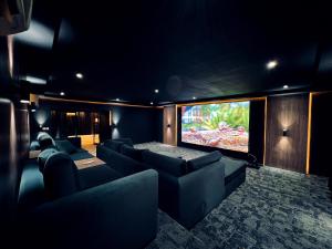 a cinema room with couches and a flat screen tv at AL JUNAIDI FARM BY BRIDGE RETREATS in Sharjah