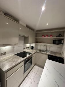 a kitchen with white cabinets and a sink at Luxury Stay near London Eye zone 1 in London