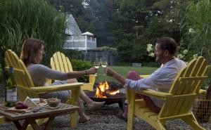 a man and woman holding glasses of wine sitting around a fire at Abbey's Lantern Hill Inn in Ledyard Center