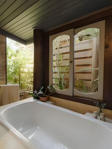 uma casa de banho com banheira e 2 espelhos em Studio Thai na praia em Imbituba