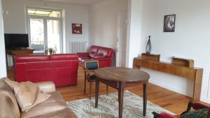 ein Wohnzimmer mit einem roten Sofa und einem Tisch in der Unterkunft La Maison Barent - Proche des grottes de Rouffignac in Rouffignac Saint-Cernin
