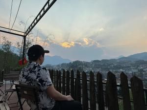 una mujer sentada en un banco viendo la puesta de sol en Central Sapa Serenity Homestay en Sa Pa