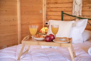a tray of fruit and drinks on a bed at Wooden House Apartments in Kaláthenai