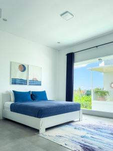 een slaapkamer met een bed met blauwe kussens en een raam bij Villa Linns in Kerobokan