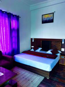 een slaapkamer met een bed met paarse gordijnen en een bank bij Himalayan Canvas in Khajjiar 