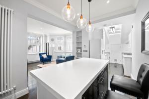 a kitchen with a white counter and some chairs at South Kensington Luxury Suite in London