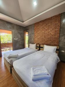 two twin beds in a bedroom with a brick wall at The Beatles Lagoon in Ban Na Bon