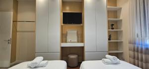 two twin beds in a room with a tv at 2SE Apartment in Korçë +36 photos