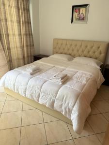ein Bett mit weißer Bettwäsche und Handtüchern darauf in der Unterkunft Comfort Apartments Promenade in Sarandë