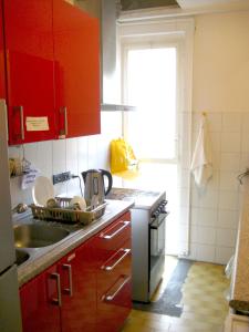 kuchnia z czerwonymi szafkami, umywalką i oknem w obiekcie Panda Hostel w Mediolanie
