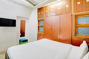 1 dormitorio con cama blanca y armarios de madera en OYO Hotel Rose Valley en Indore