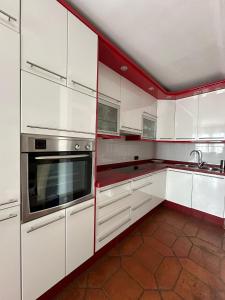 ネルハにあるNerja's center Apartmentの白いキャビネットと赤のアクセントが施されたキッチン