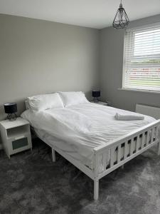 a white bed in a bedroom with two night stands at Thornaby Apartment in Thornaby on Tees