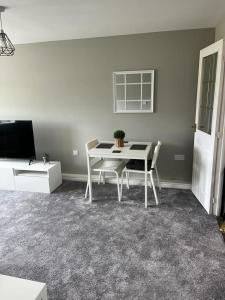 a living room with a table and chairs and a tv at Thornaby Apartment in Thornaby on Tees